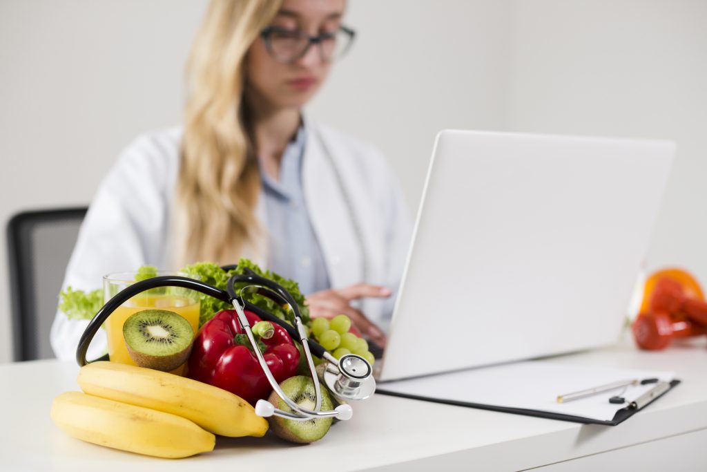 kobieta lekarz z owocami i laptopem na biurku