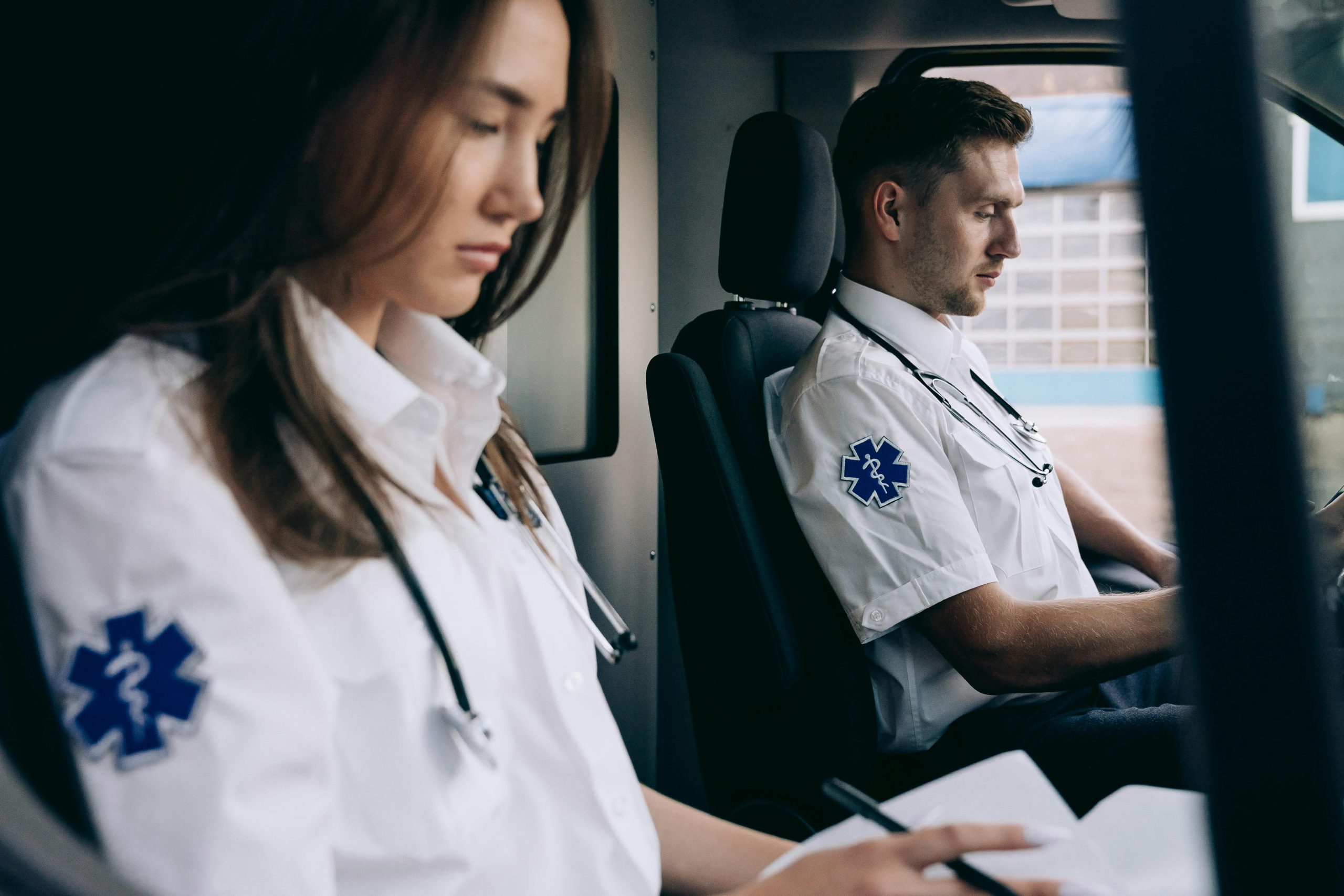 Ratownicy medyczni siedzący z przodu karetki noszący odzież mundurowa