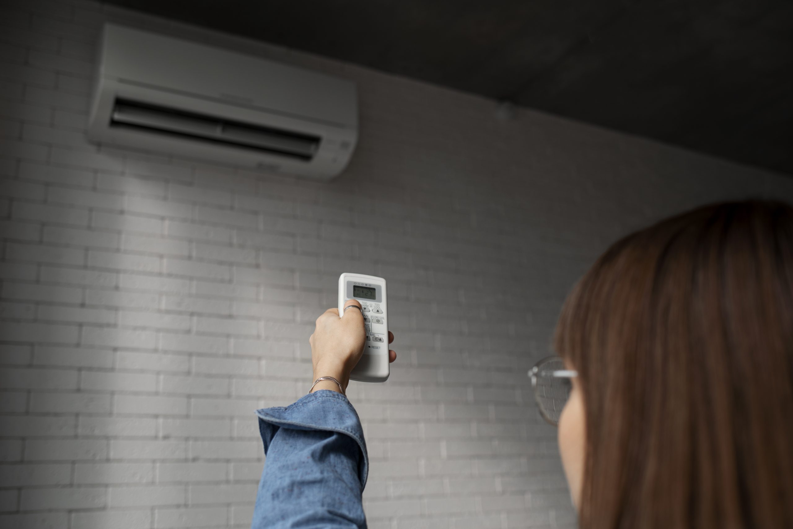 Kobieta włączająca klimatyzację w mieszkaniu – komfortowa klimatyzacja w domu w Krakowie