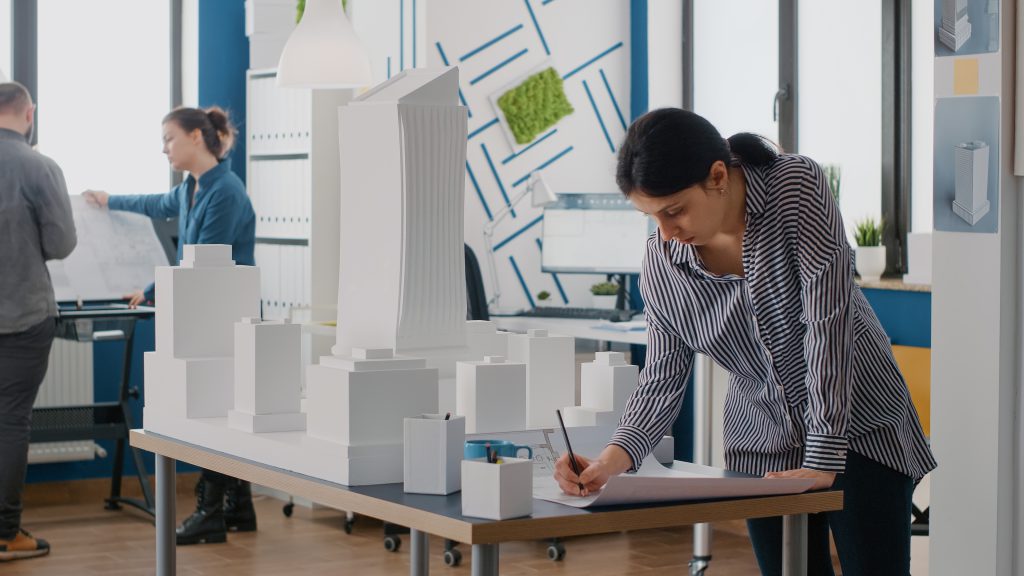 Architekt pracujący nad makietą budynku w biurze projektowym, prezentujący proces modelowania 3D w budownictwie